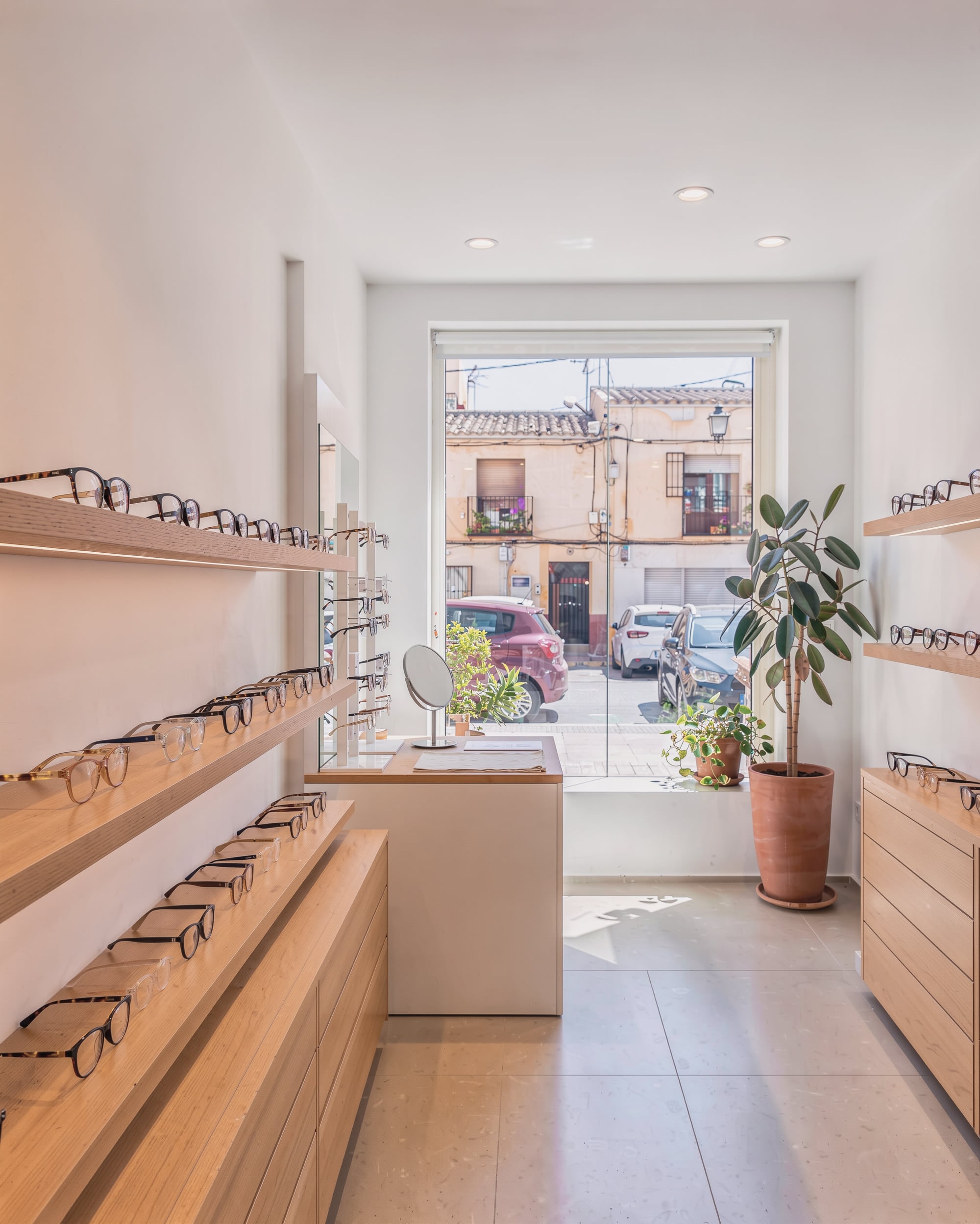 Interior de una óptica con monturas en baldas de madera